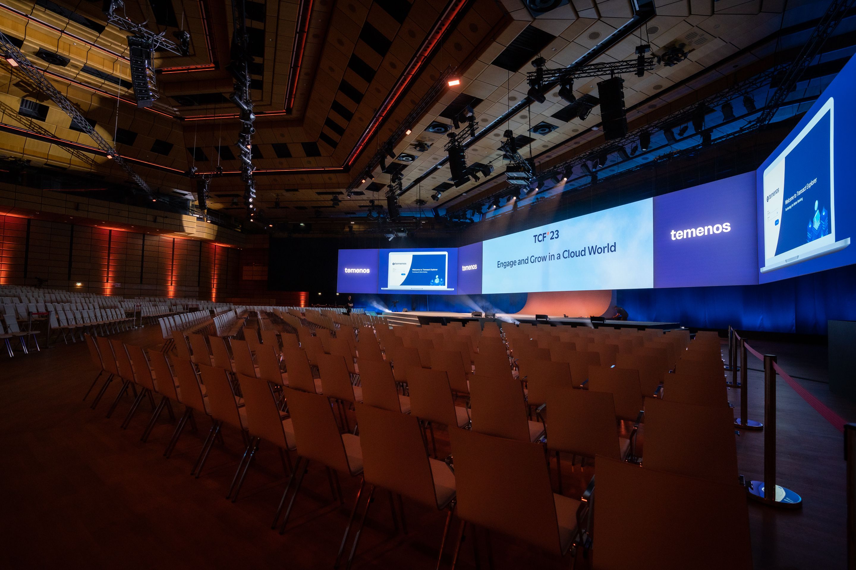 Foto: Dunkler Saal mit Sitzreihen und gebognener beleuchteter Buehnenwand