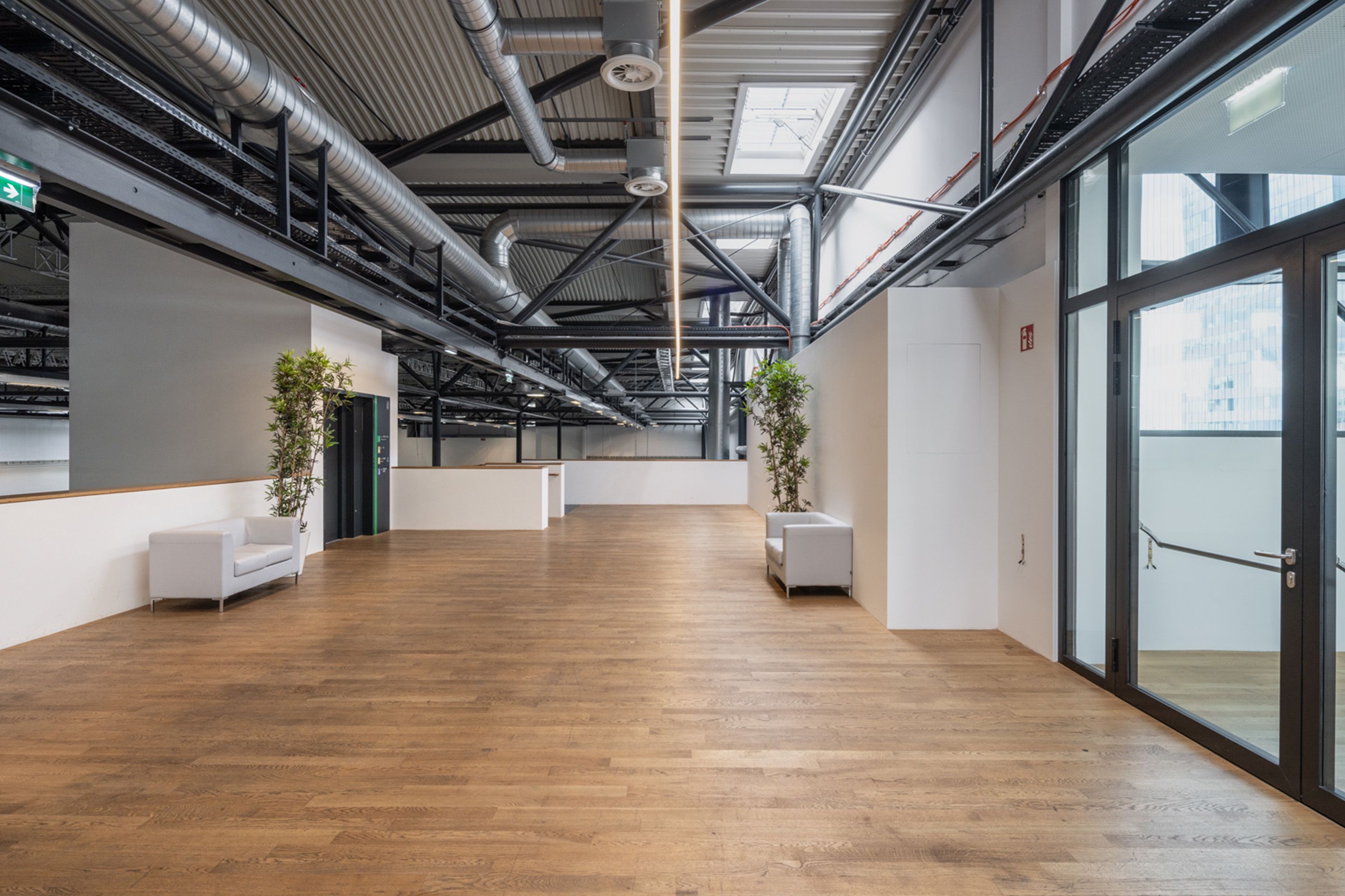 Foto: Eingangstuer mit Holzboden, hellen Moebeln und einem Lift in einer Halle