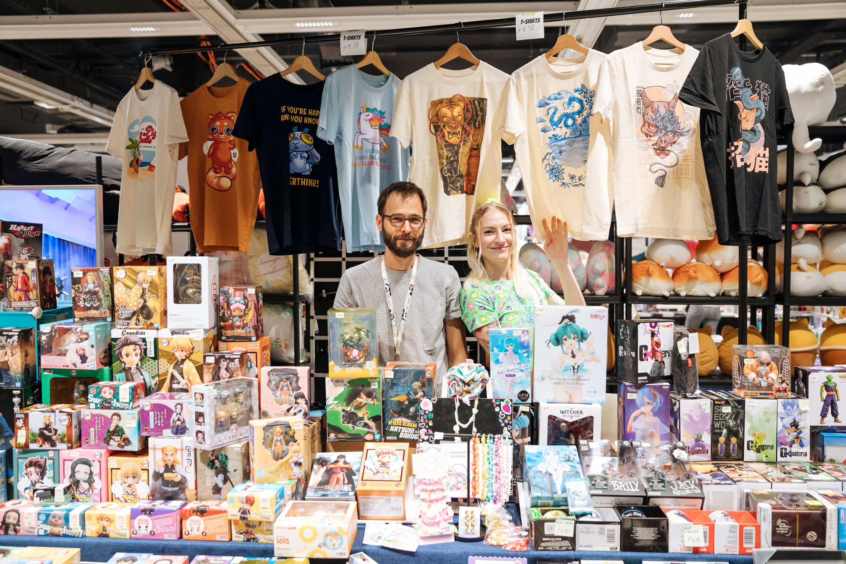 Foto: junger Mann und Frau hinter einem Verkaufsstand mit Manga Produkten