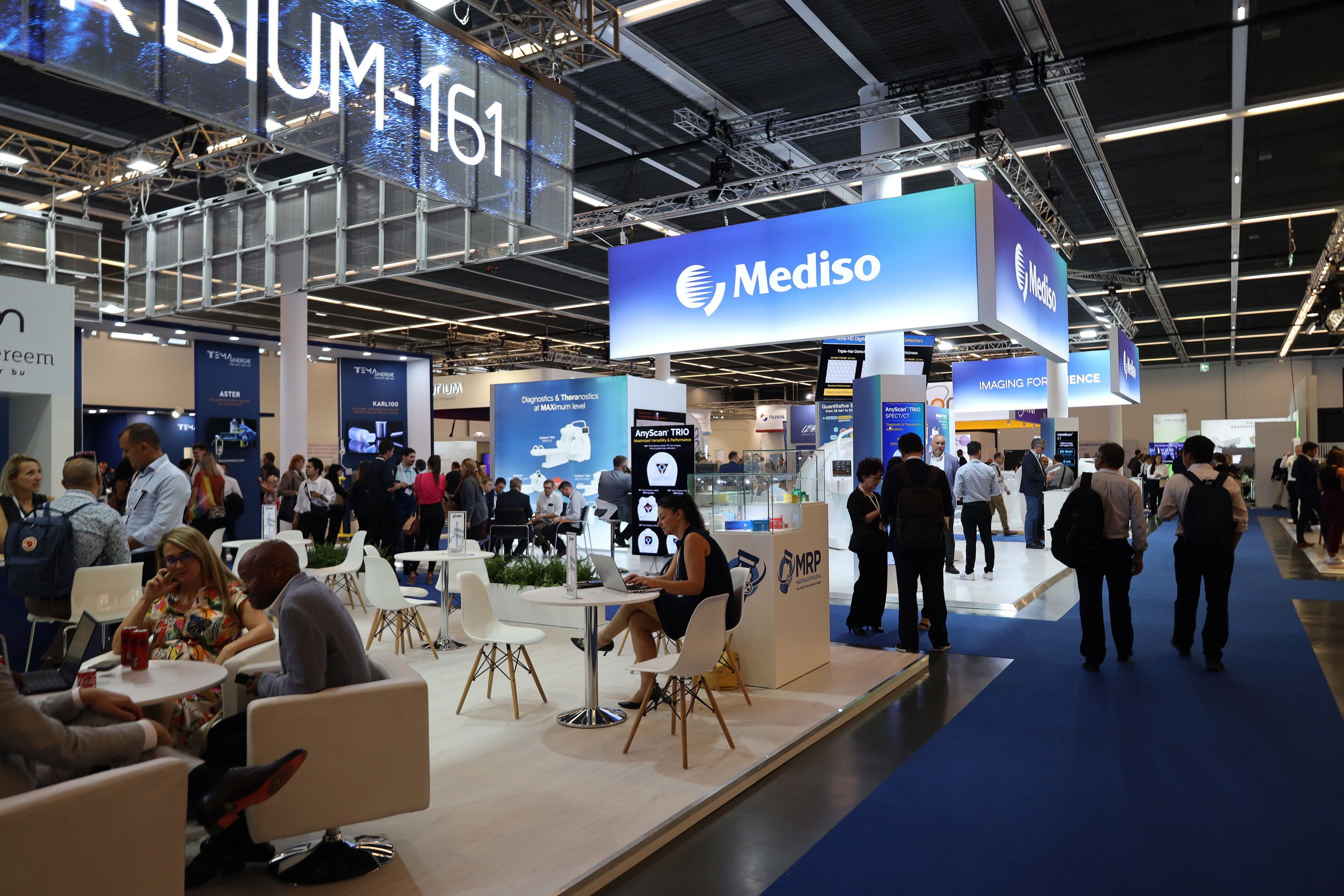 Foto: Eine Halle voller Menschen und Messestaenden mit blauen Teppich