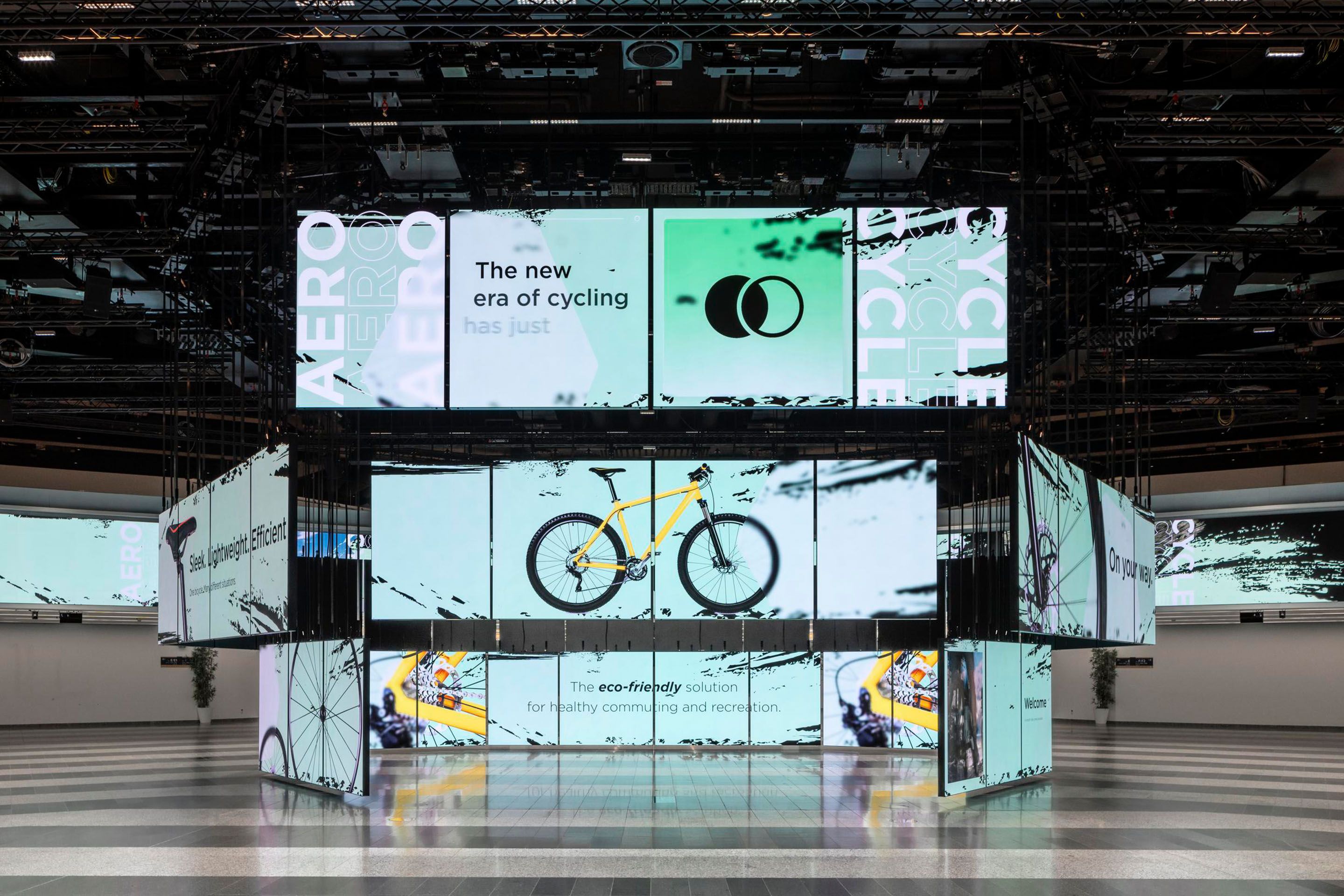 Foto: beleuchtete LED Paneele mit verschiedenen Grafiken eines gelben Rades in einer Halle