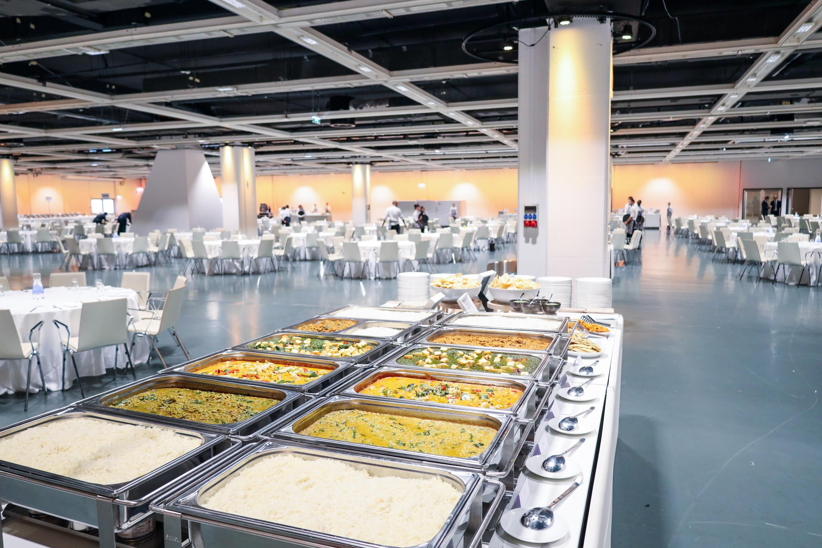 Foto: Halle mit runden Galatischen und Stuehlen in weiss mit Buffet