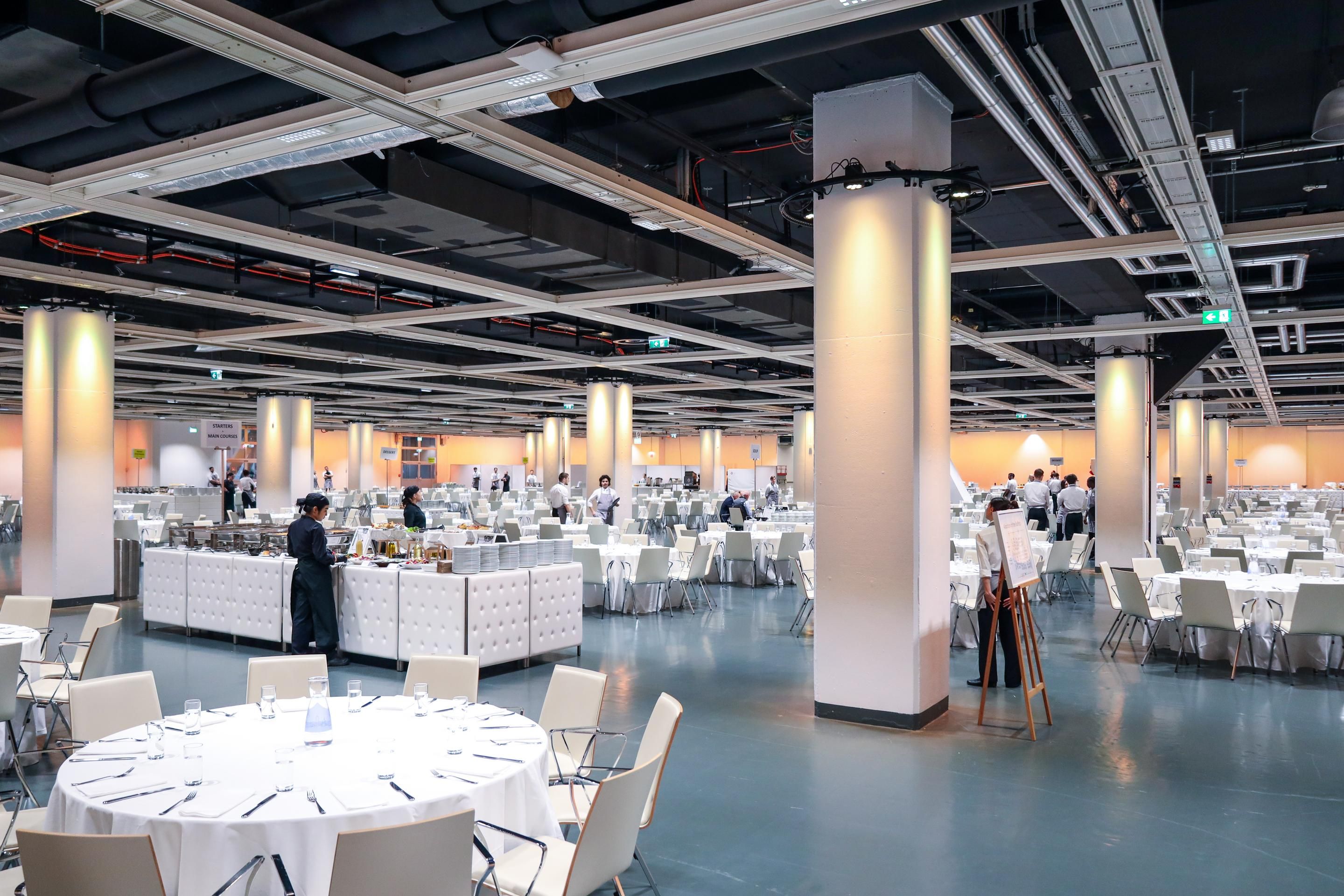 Foto: Halle mit runden Galatischen und Stuehlen in weiss mit Buffet