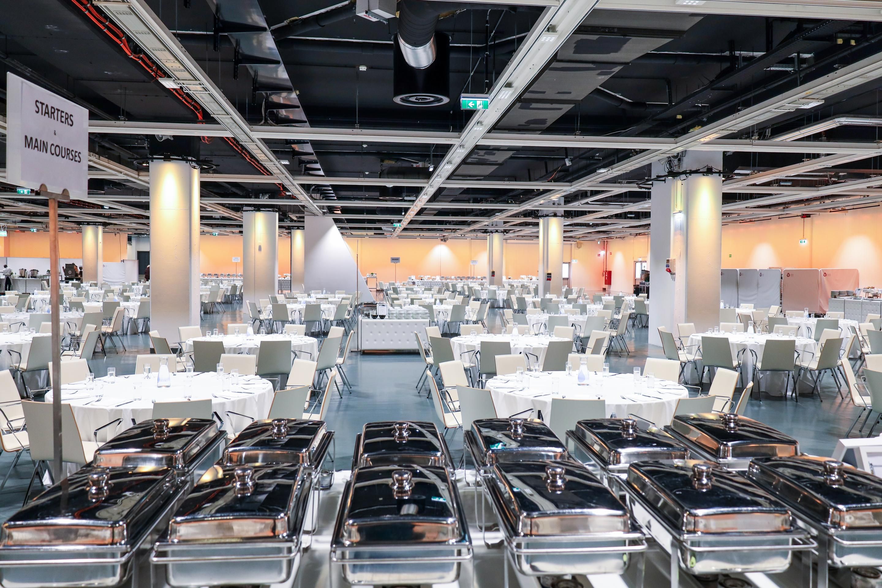 Foto: Halle mit runden Galatischen und Stuehlen in weiss mit Buffet