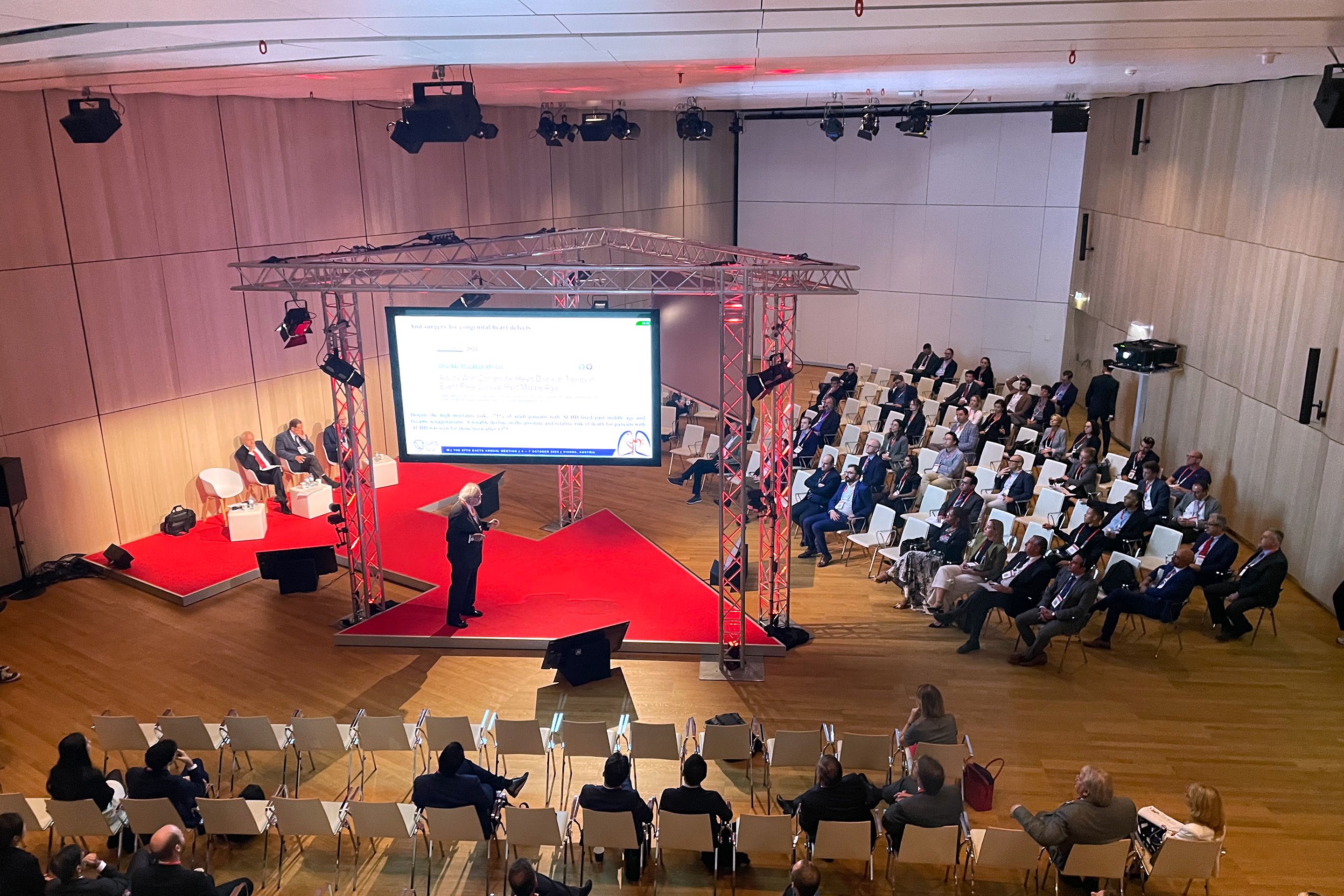 Foto: Raum mit Vortragendem im Zentrum, kreisfoermigen Sesselreihen und Leinwand