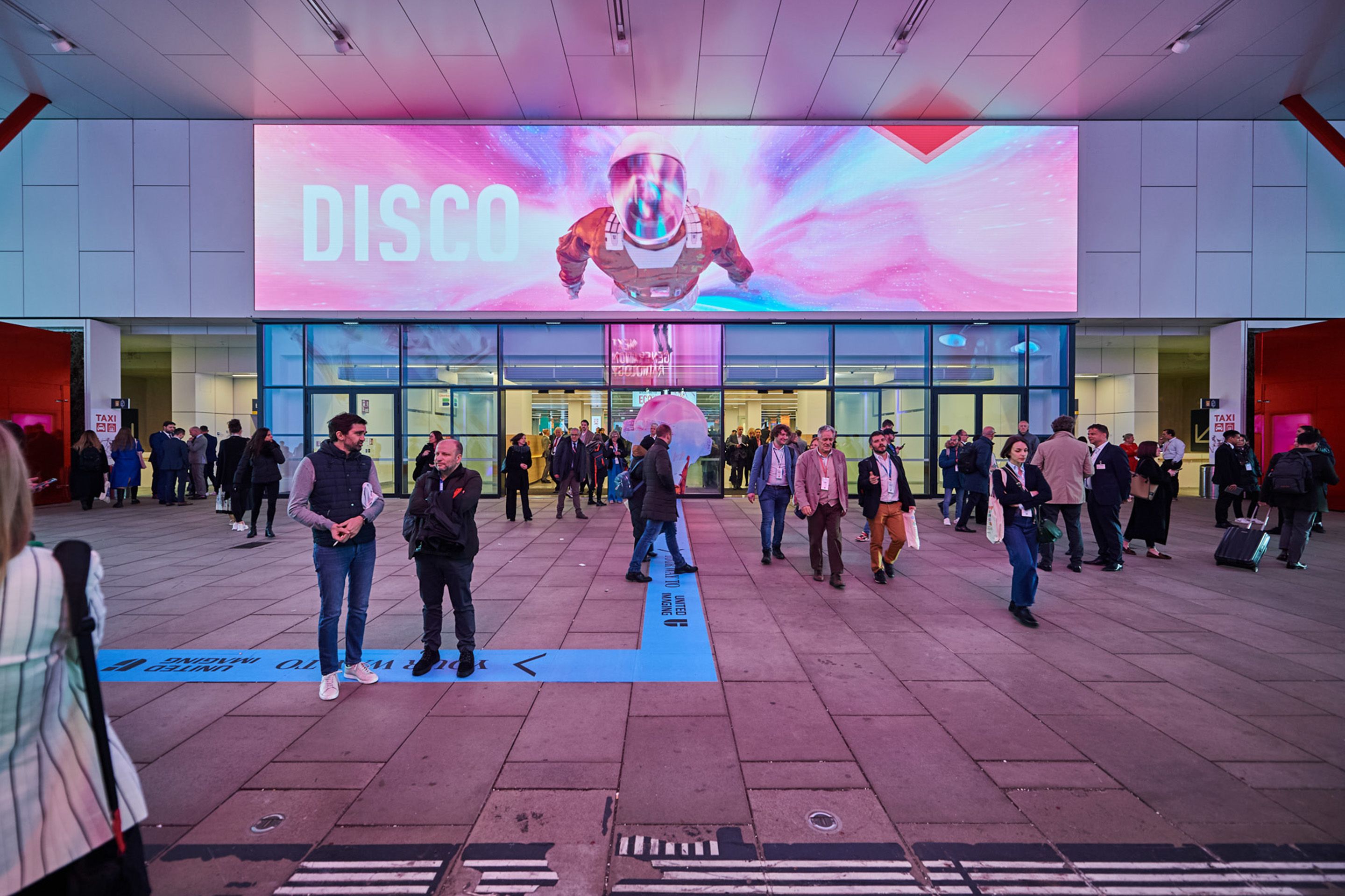 Foto: Eingang mit LED Screen und vielen Menschen