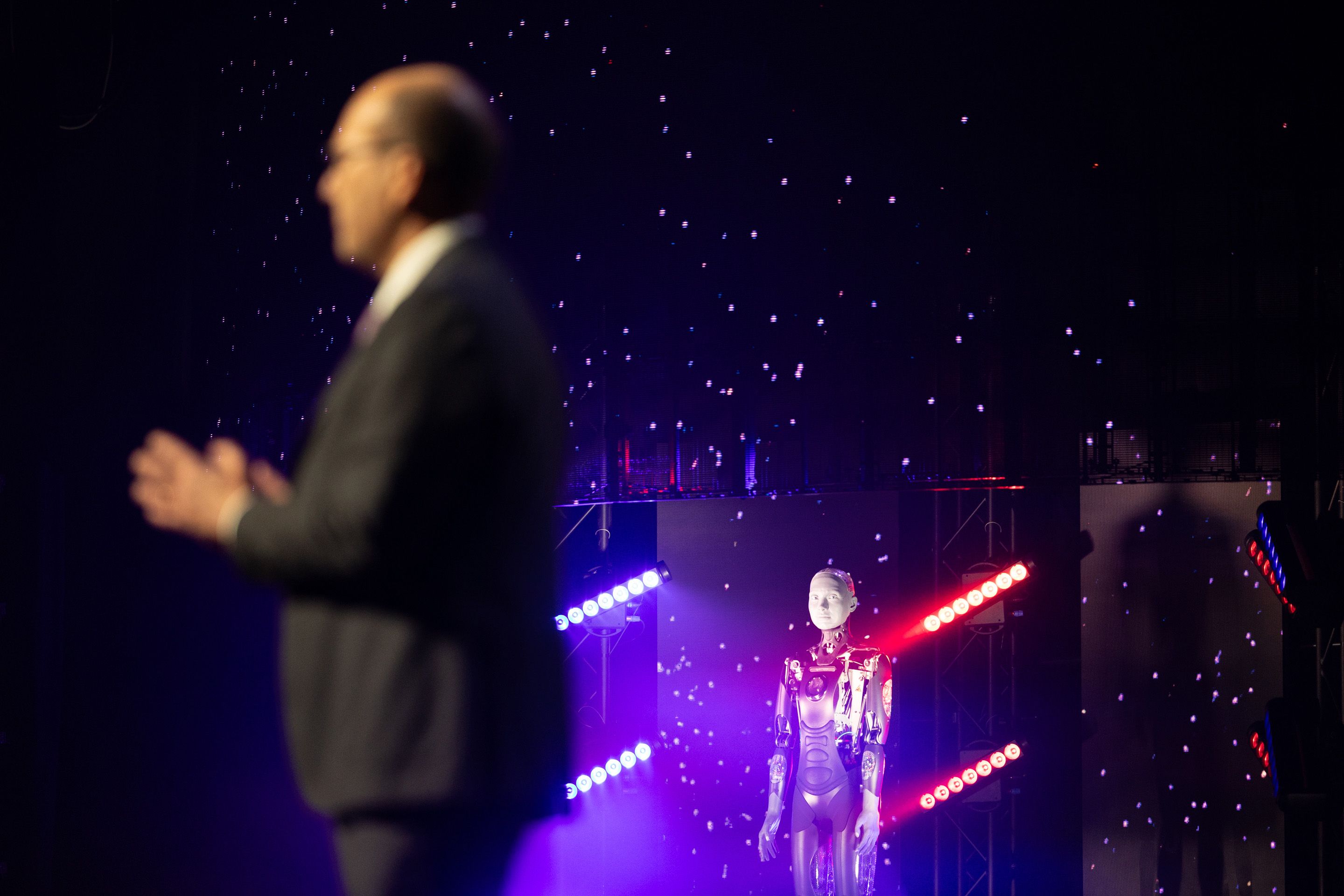 Foto: Mann im Vordergrund, verschwommen. Im Hintergrund ein Roboter