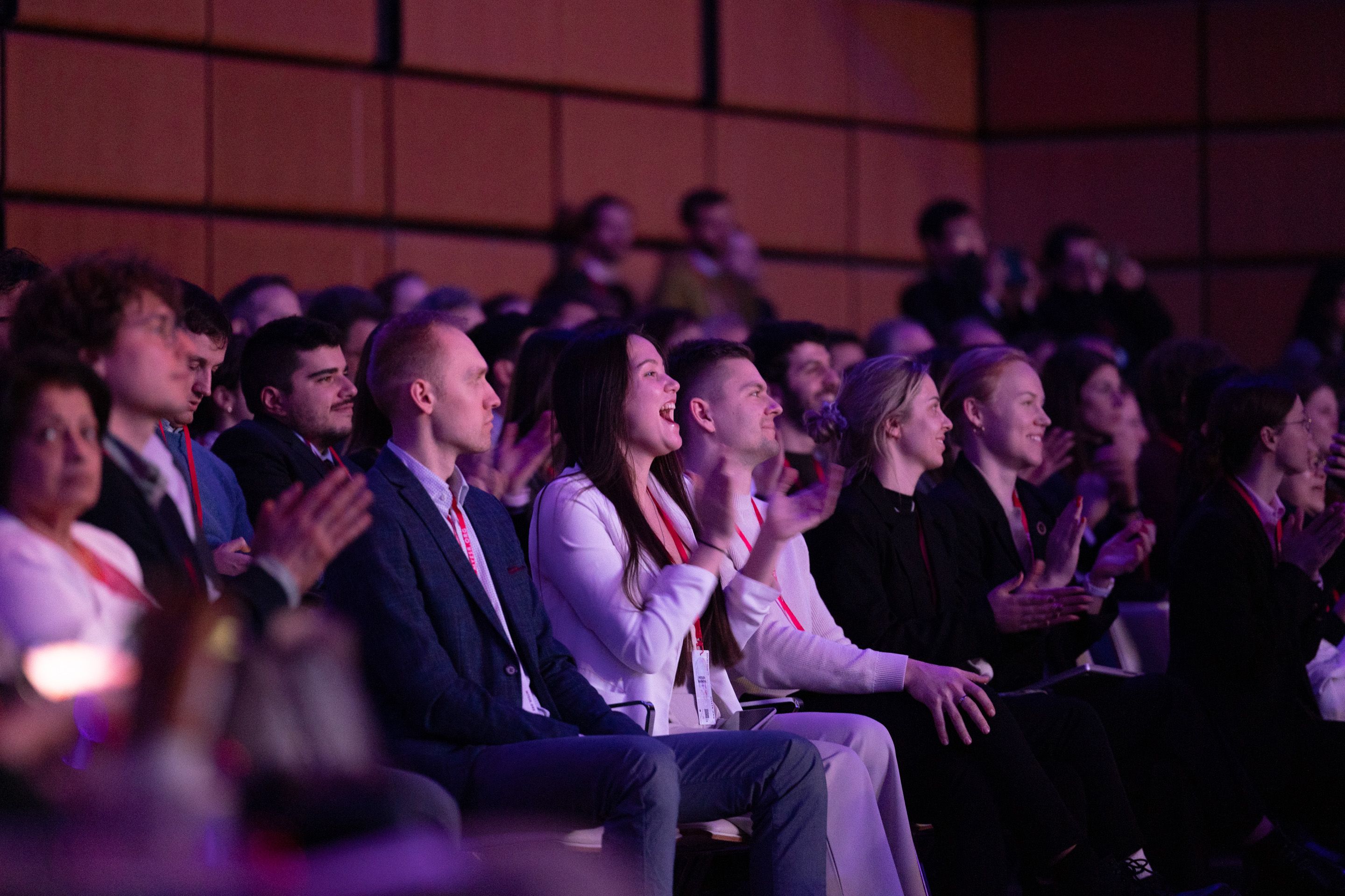 Foto: sitzende Menschen in einem dunklen Raum applaudieren