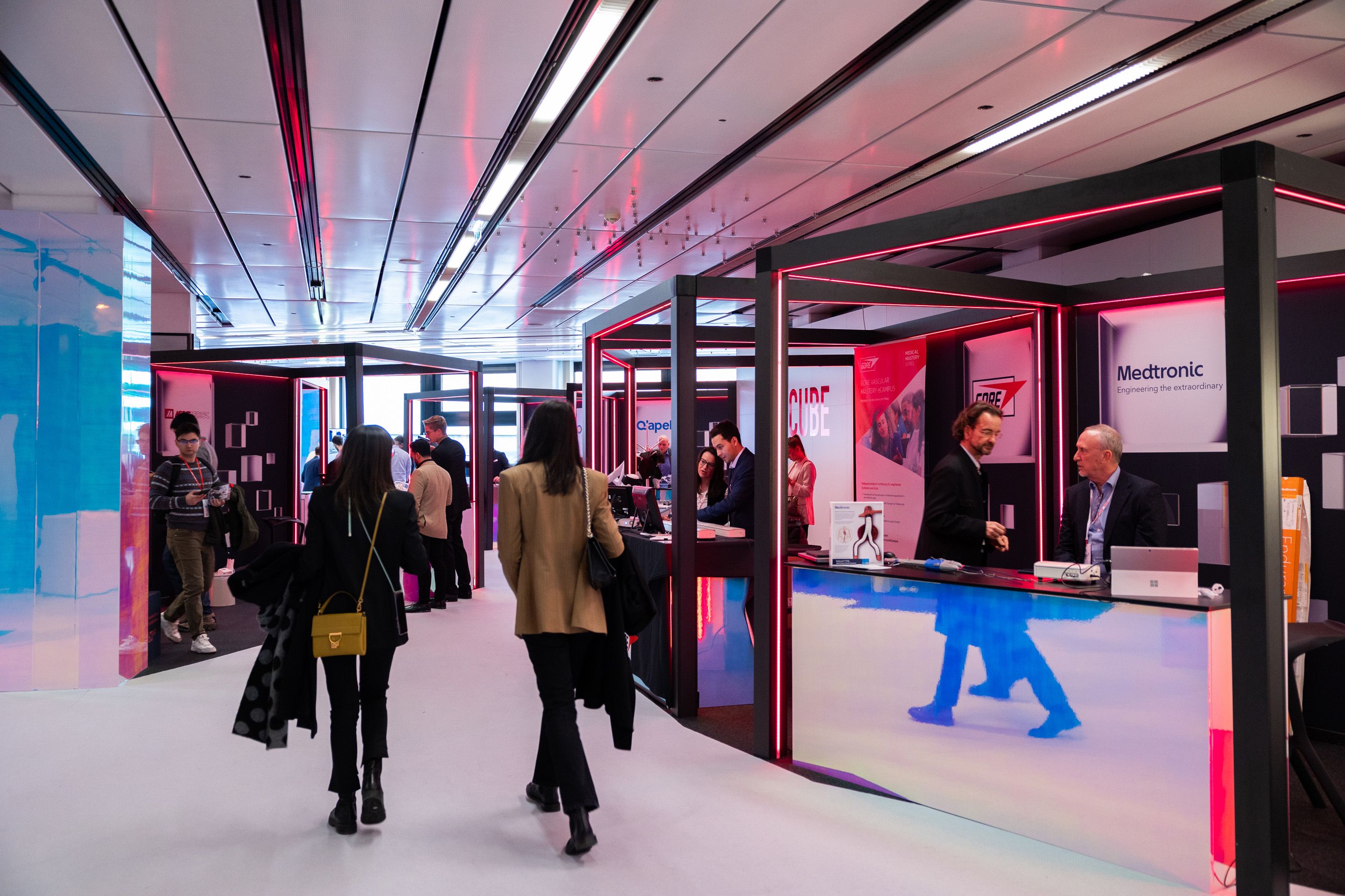 Rot beleuchtete Messestaende in einem Raum mit Menschen