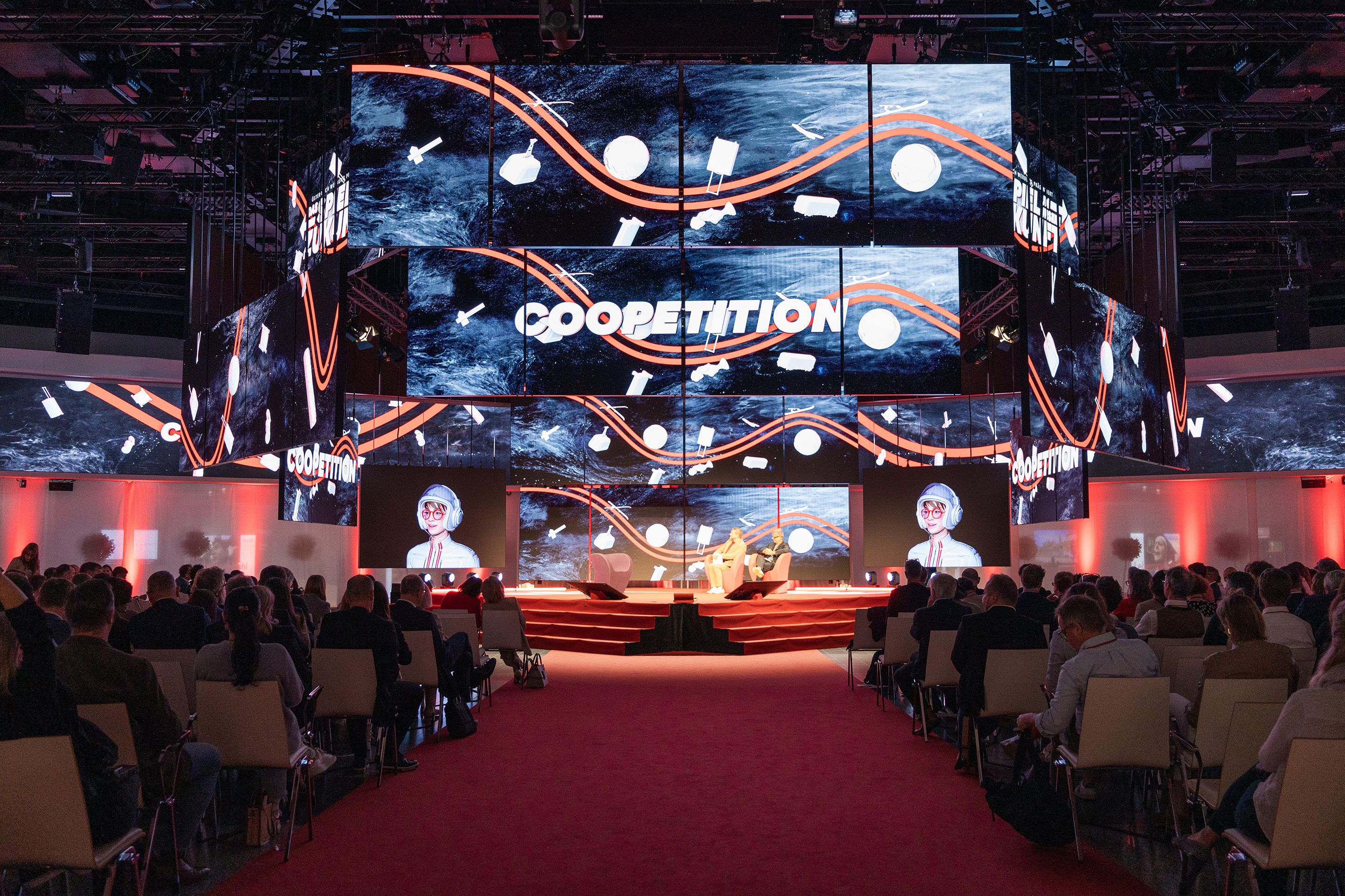 Einige Speaker sitzen auf der polySTAGE Buehne vor Publikum im Austria Center Vienna.