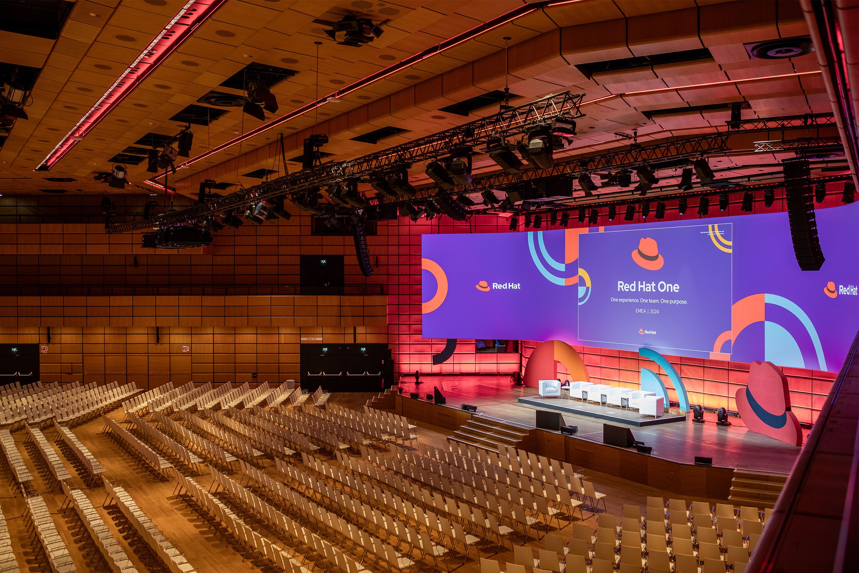 Violett beleuchtete Leinwand in einem großen, leeren Saal mit vielen Sitzreihen.