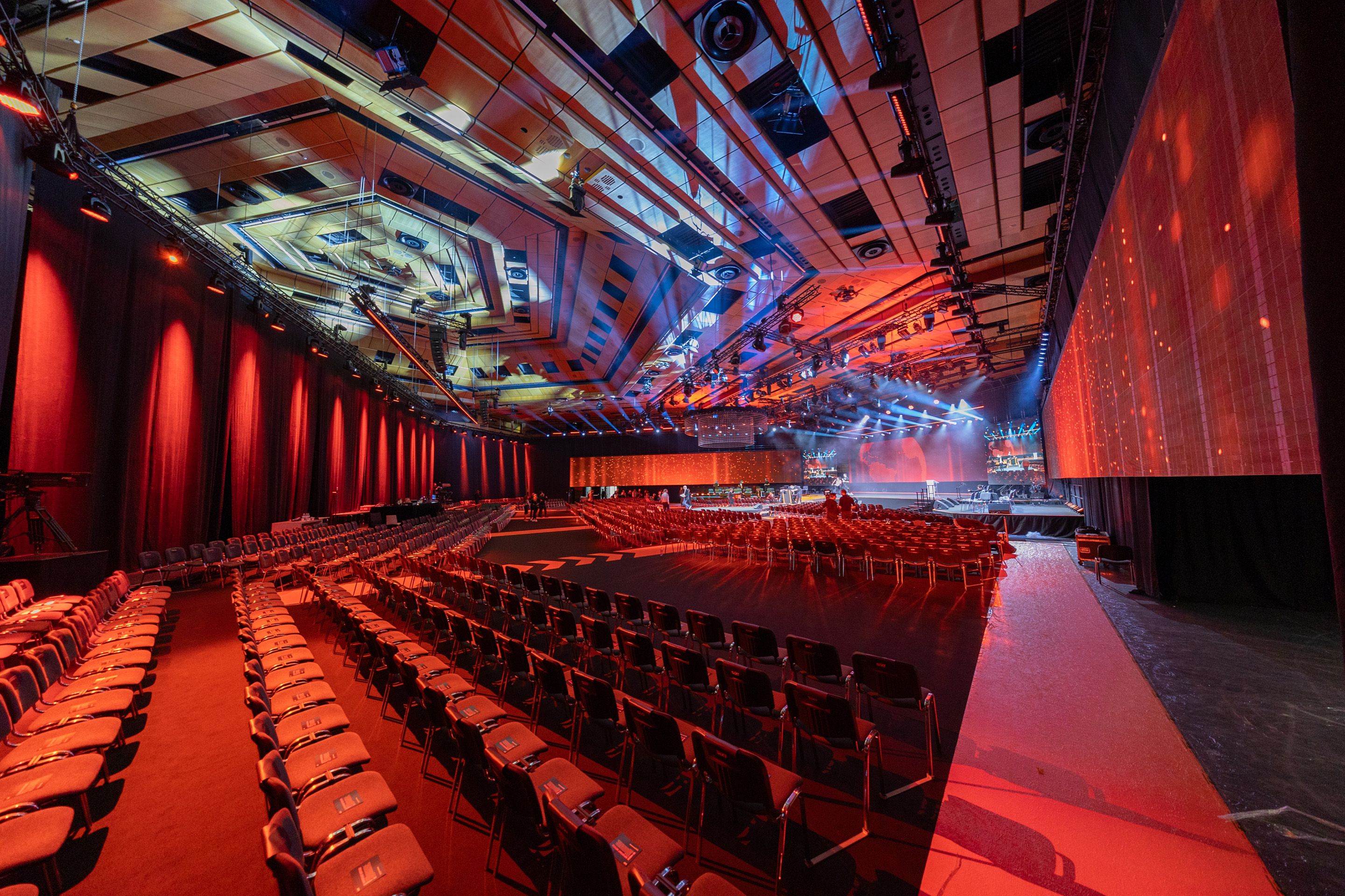 Saal A im Austria Center Vienna mit Buehne und roten Teppich in roter Beleuchtung.