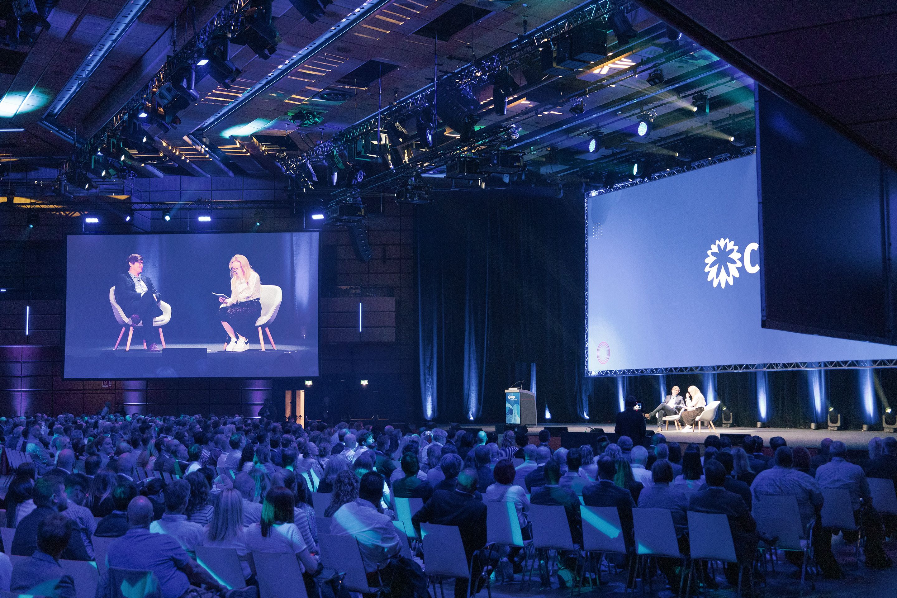 Sitzreihen voll Menschen blicken auf die Buehne von Saal A bei einem Corporate Event im Austria Center Vienna.