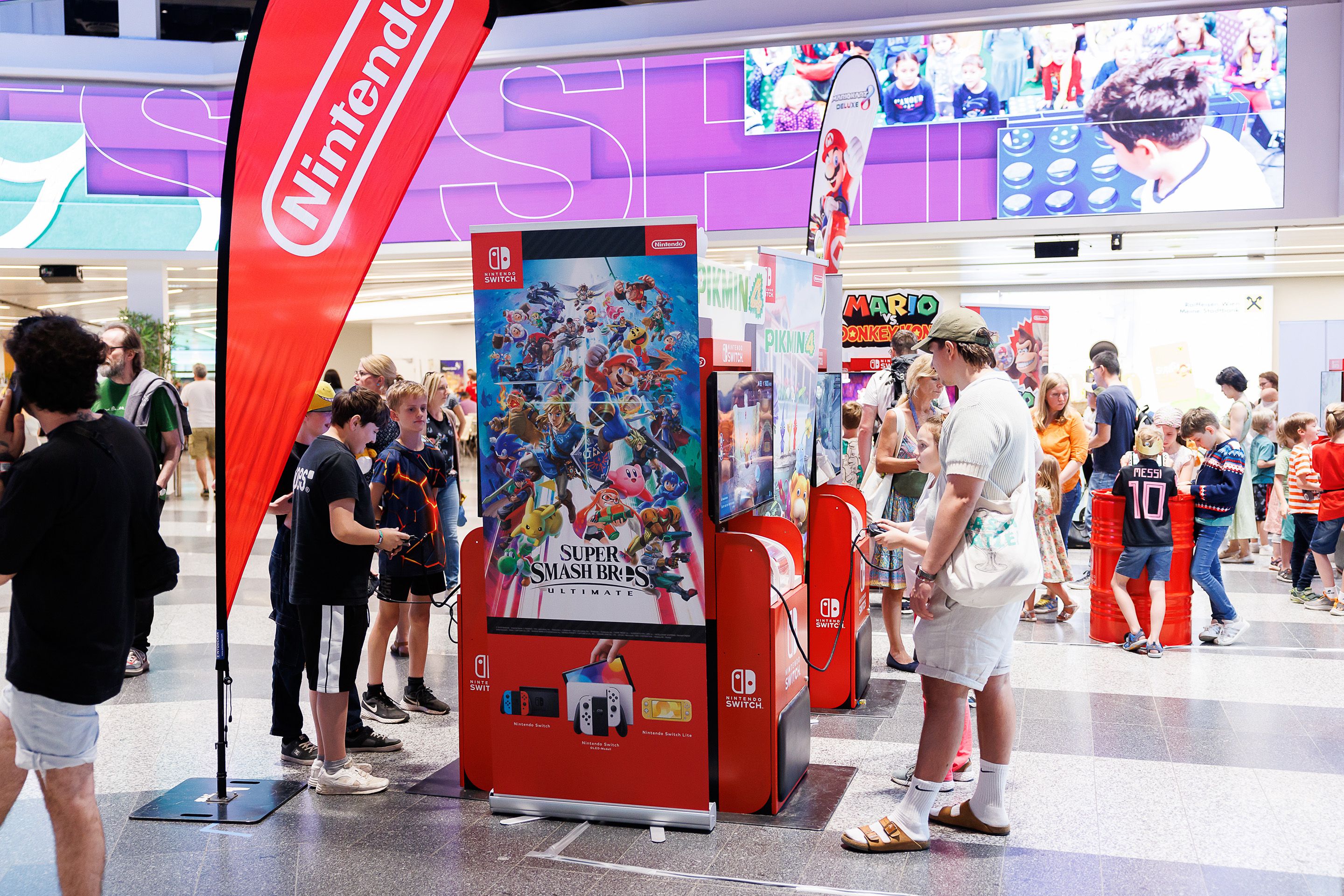 Besucherinnen spielen an Spielautomaten in der Eingangshalle des Austria Center Vienna am Spielefest 2024.