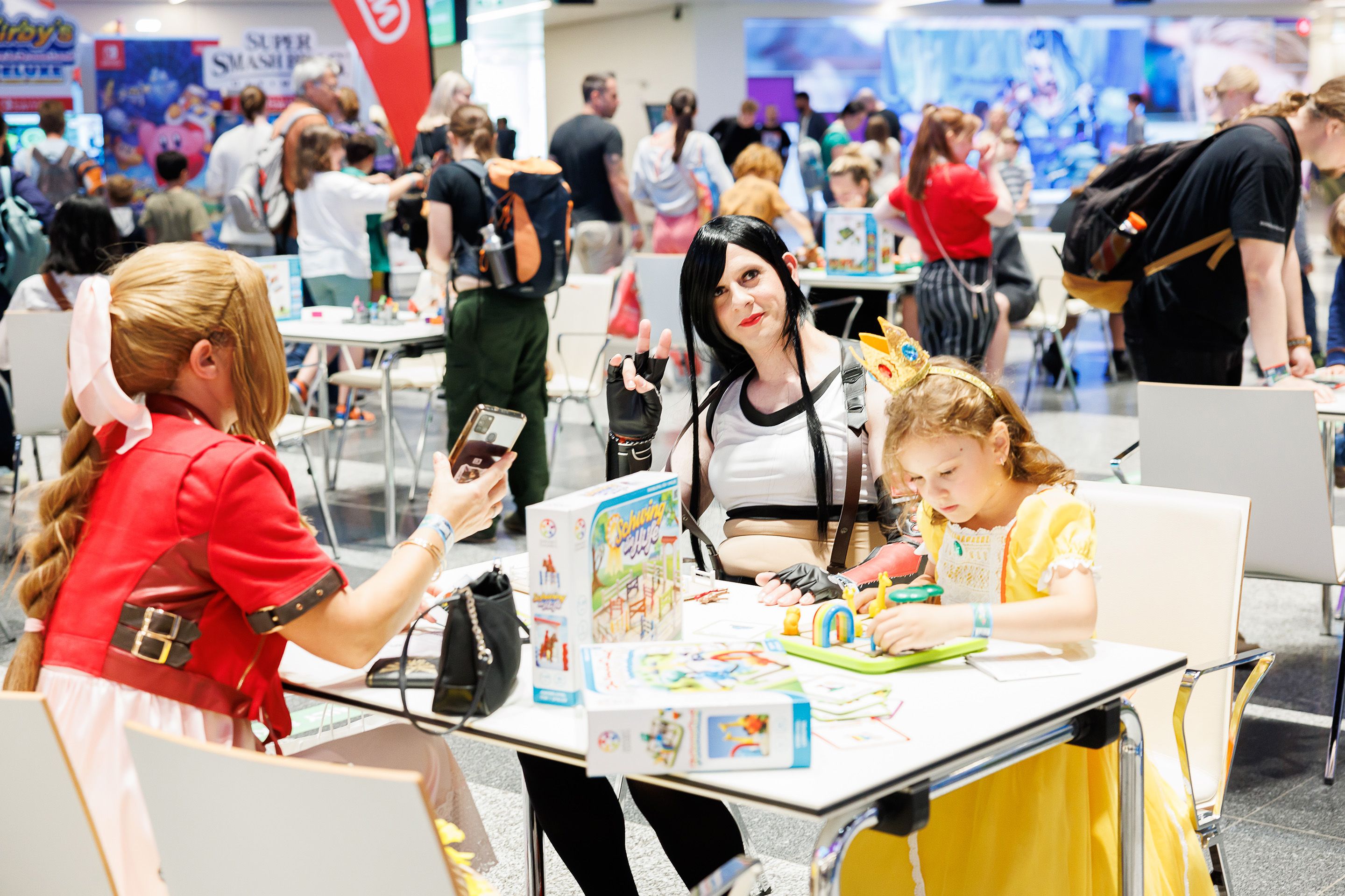 Frau mit Kindern verkleidet an einem Spieltisch in der Eingangshalle des Austria Center Vienna.