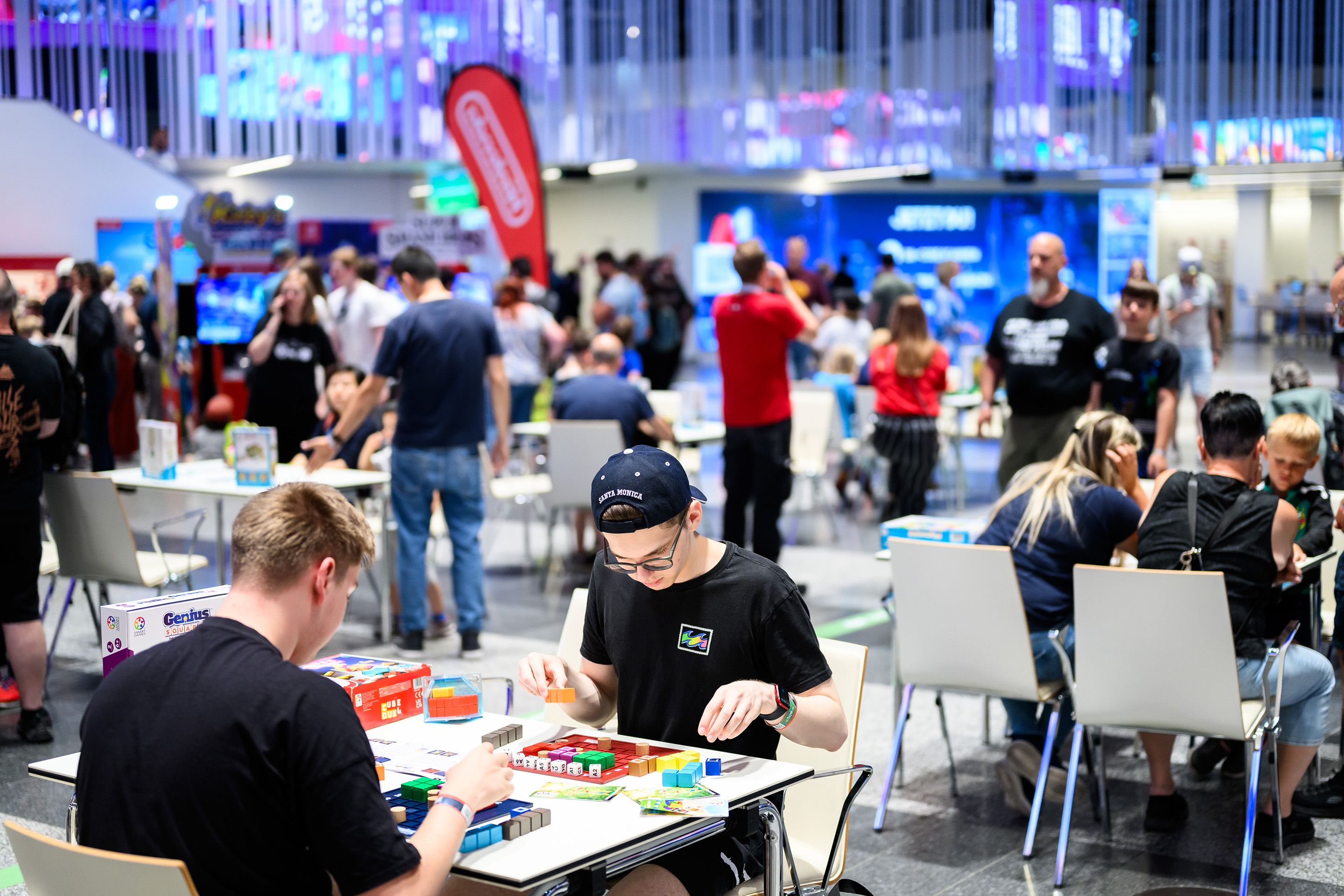 Besucherinnen spielen Brettspiele in der Eingangshalle des Austria Center Vienna am Spielefest 2024.