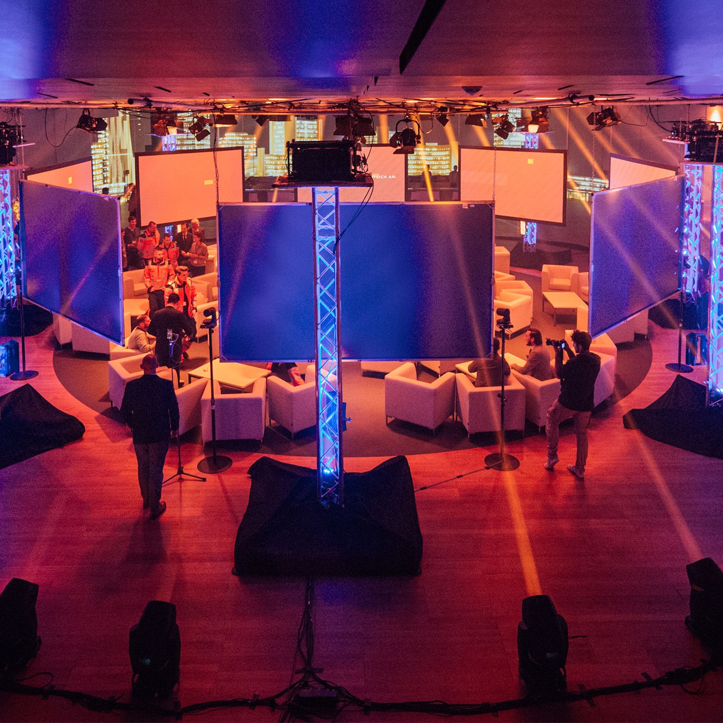 Hybrides Eventsetting im Austria Center Vienna mit Sitzgruppe im Kreis und vielen Bildschirmen und Technikern