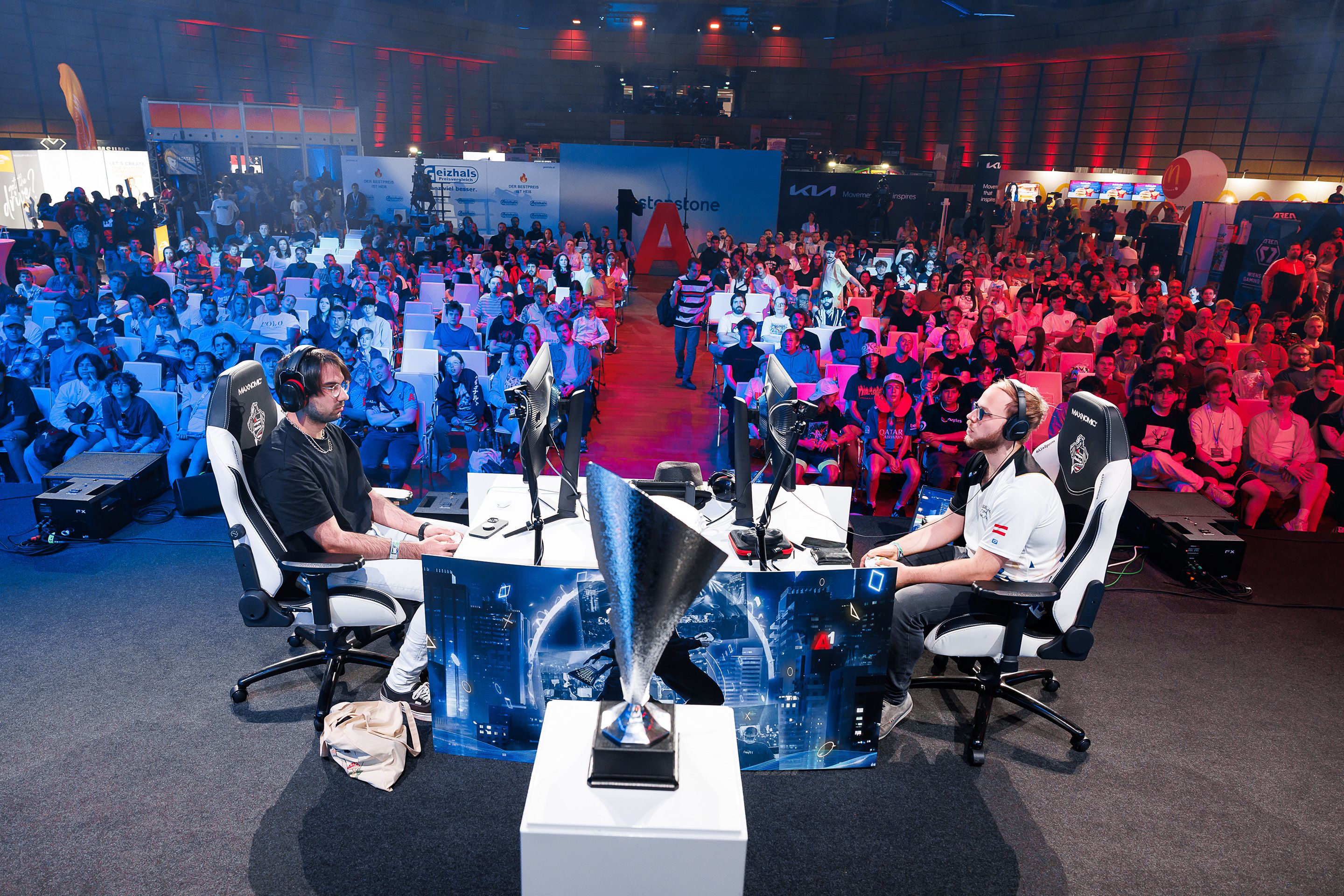 Zwei maennliche Spieler sitzen sich gegenueber und spielen vor Publikum am A1 E-Sports Festival 2024 im Austria Center Vienna.