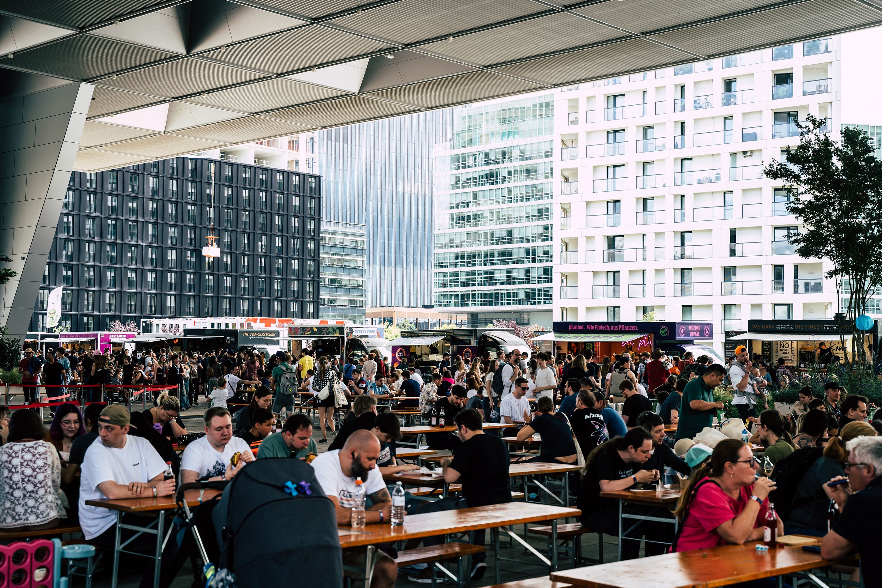 Vorplatz des Austria Center Vienna mit Foodcourt und vielen essenden Menschen.