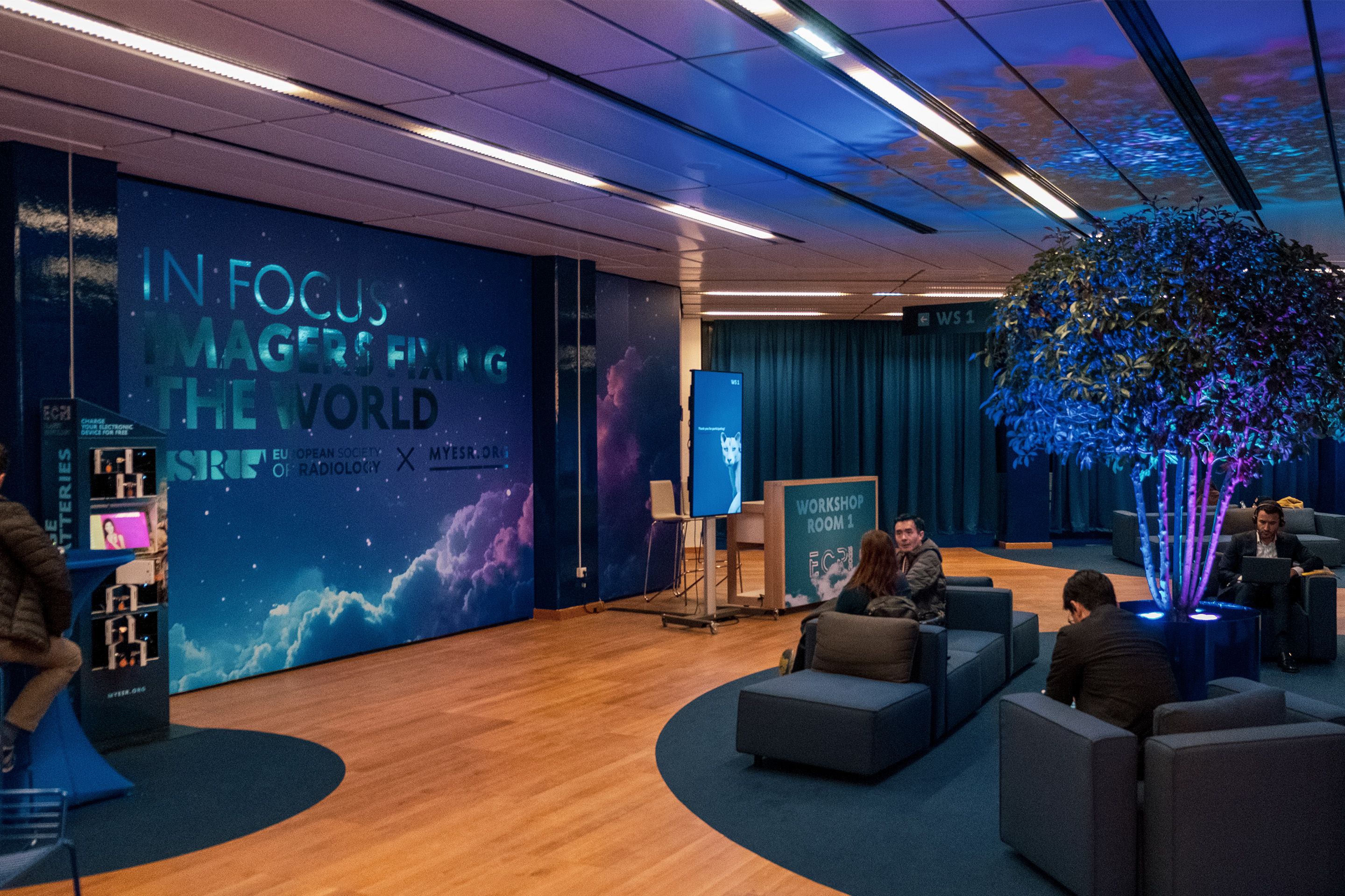 Sitzbereiche vor einem Workshopraum mit Menschen am ECR 2025 im Austria Center Vienna