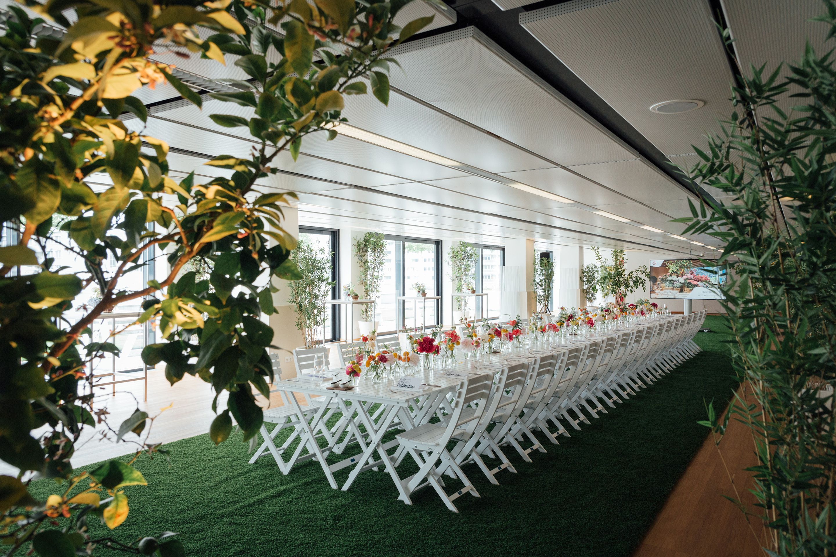 Weisse, lange gedeckte Tafel mit Blumenschmuck im hellen Rooftop Foyer im Austria Center Vienna