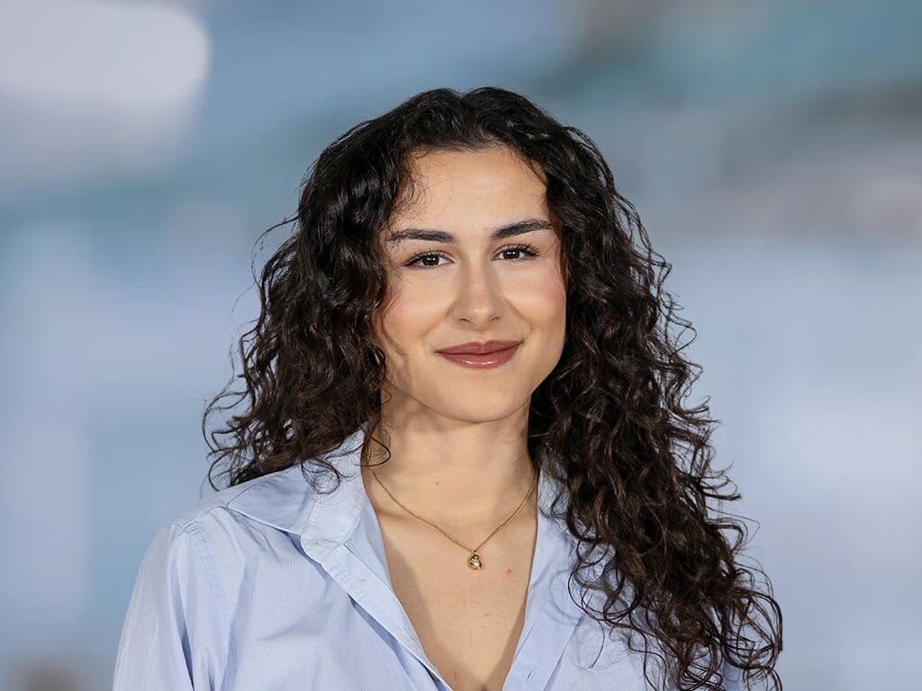 Porträt einer Frau mit lockigem Haar vor hellem Hintergrund