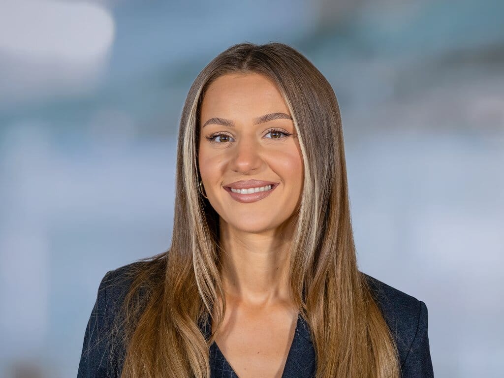 Porträt einer lächelnden Frau mit langen Haaren vor hellem Hintergrund