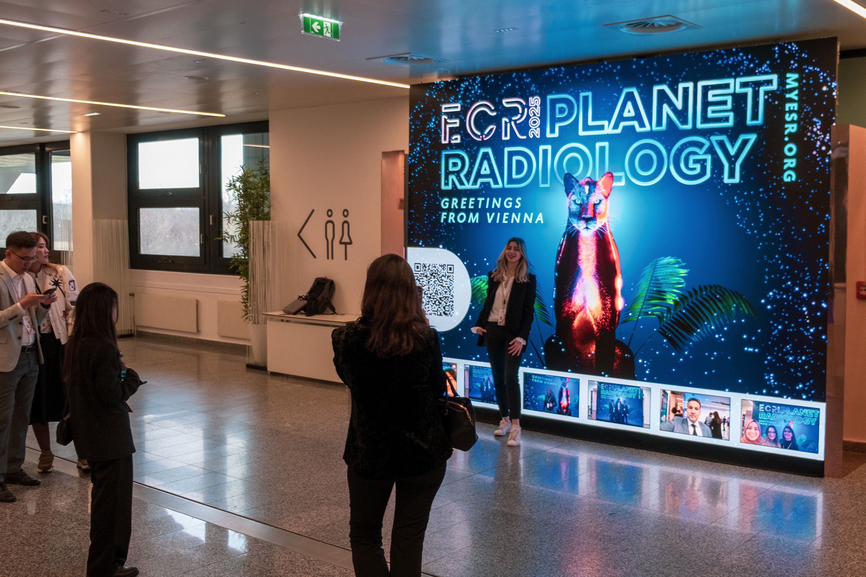 Teilnehmer fotografieren sich vor LED Foto Wall im Austria Center Vienna während des ECR 2025